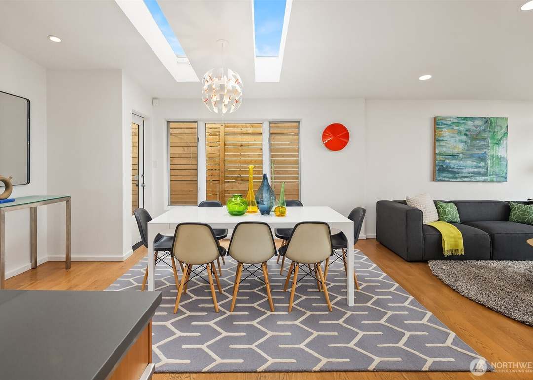 Bright mid-century modern dining room with white table and molded chairs beneath skylights