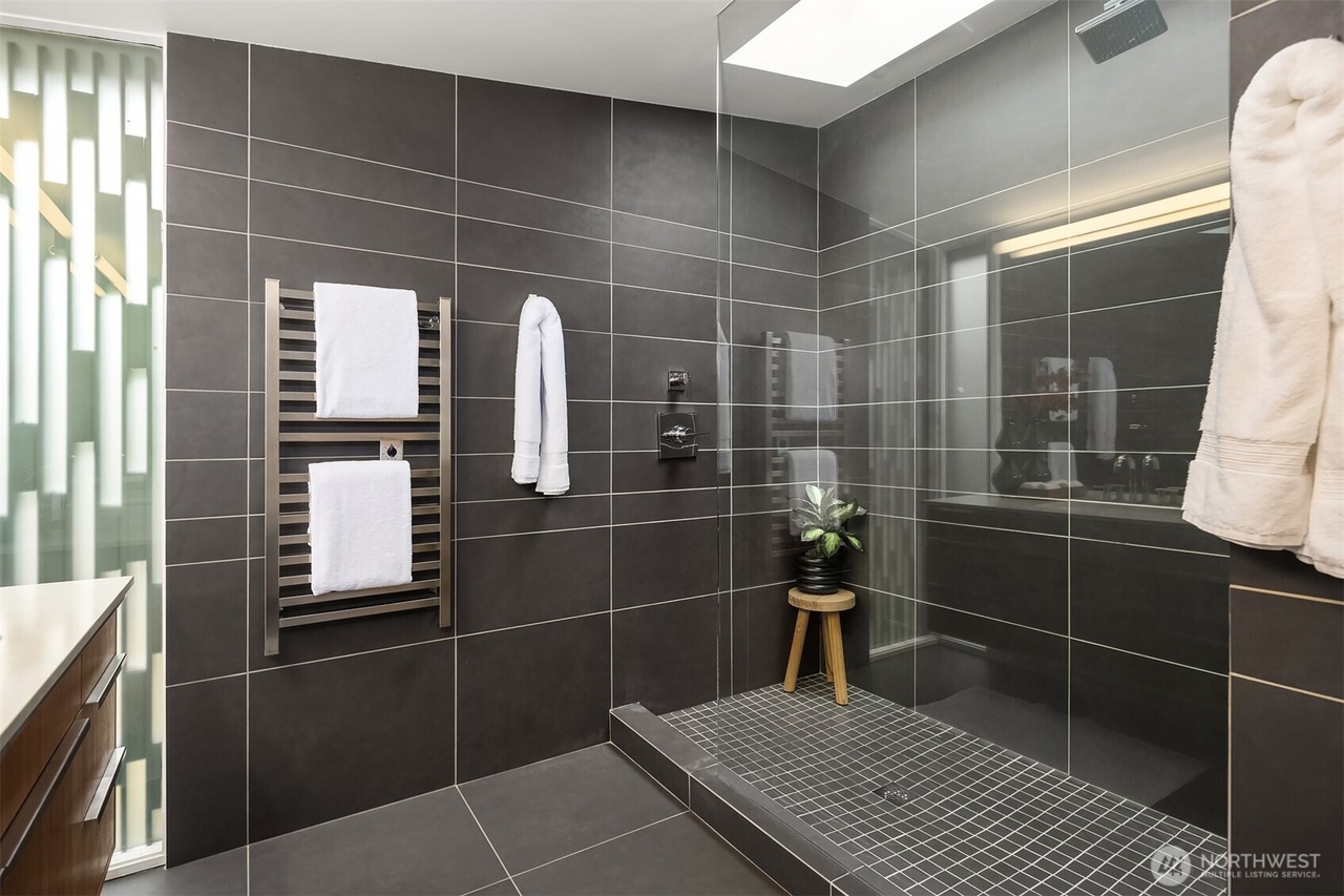 Contemporary bathroom with dark charcoal tile, glass shower, and stainless towel warmer