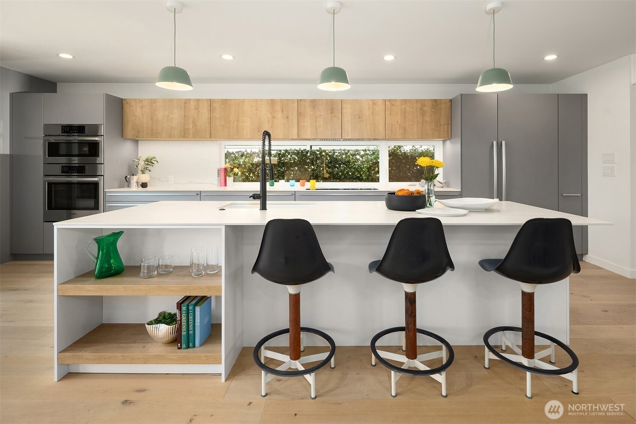 Modern kitchen island with bar stools and sage green pendant lights
