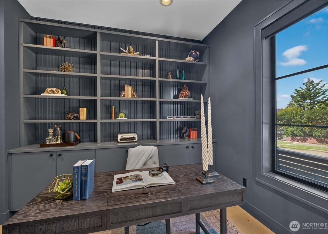 Moody contemporary home office with built-in charcoal grey bookshelves and dark wood desk