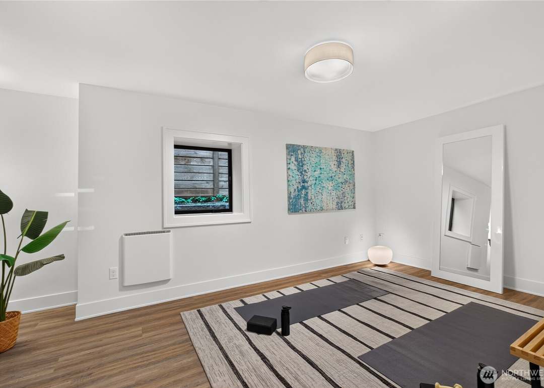 Bright minimalist home yoga studio with leaning mirror and striped rug