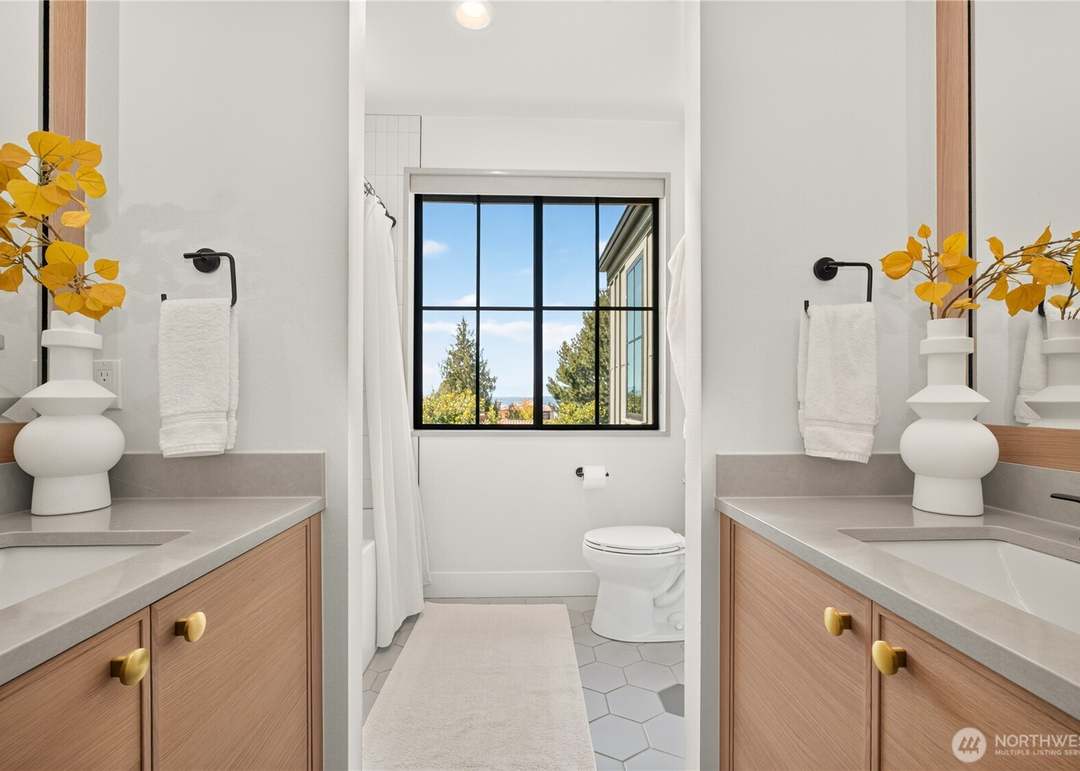 Symmetrical modern bathroom with light wood double vanity framing a window