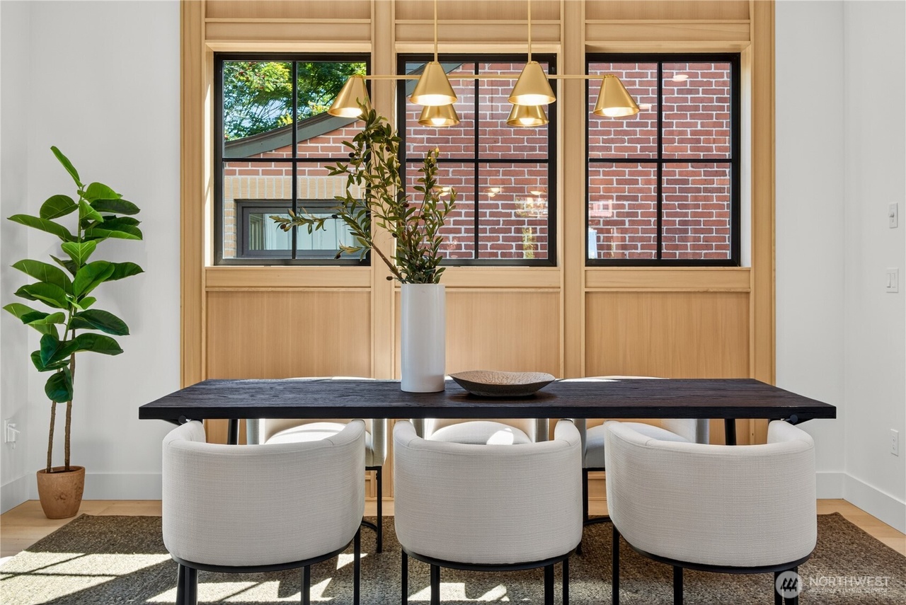 Modern dining area with dark wood table, curved upholstered chairs, and brass chandelier