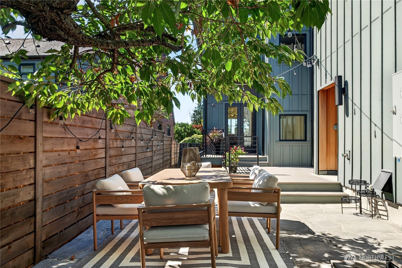 Outdoor stone patio dining area with modern wood armchairs and striped rug