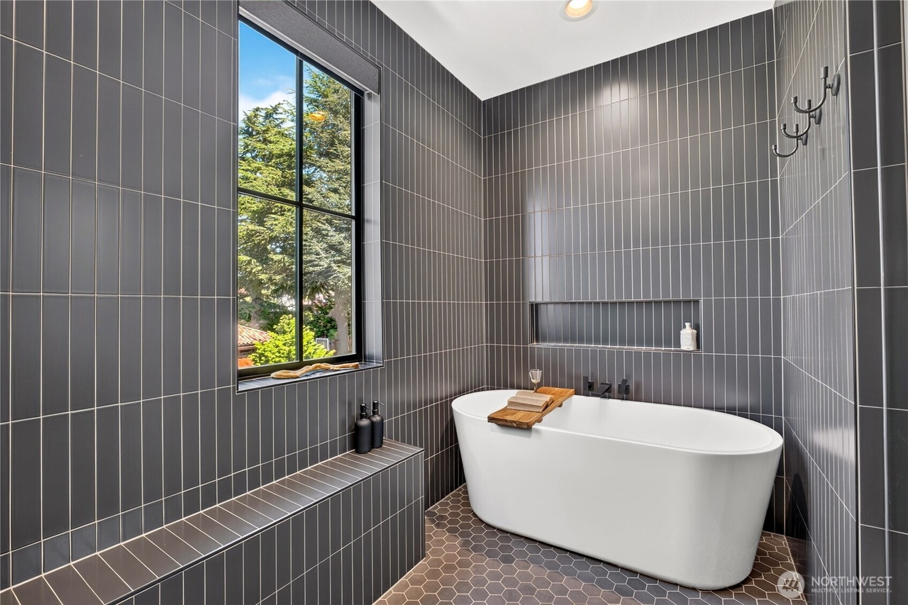Modern bathroom with freestanding soaking tub against dark vertical tile