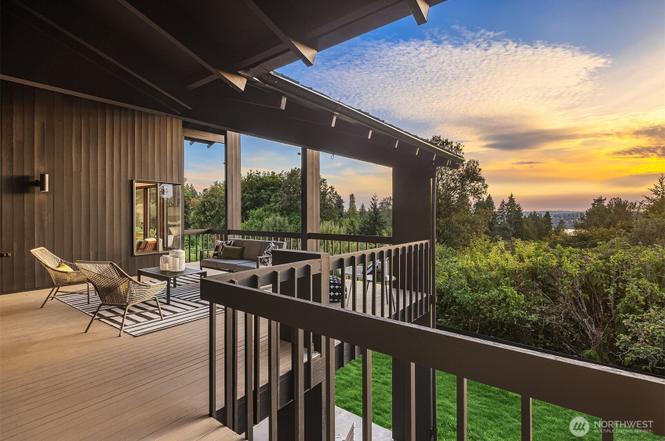 Covered outdoor wooden deck with contemporary lounge seating overlooking lush trees at sunset