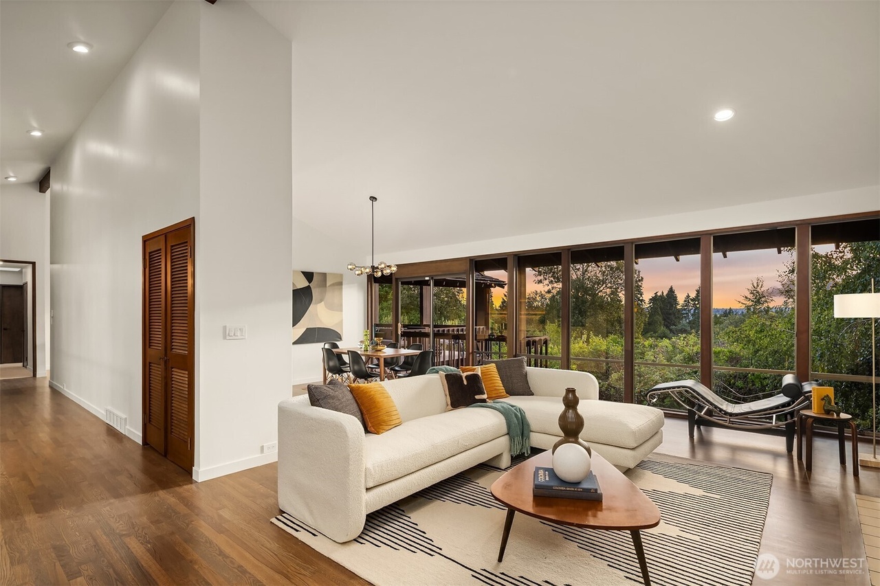 Open-concept living room with curved cream sectional and triangular wood coffee table