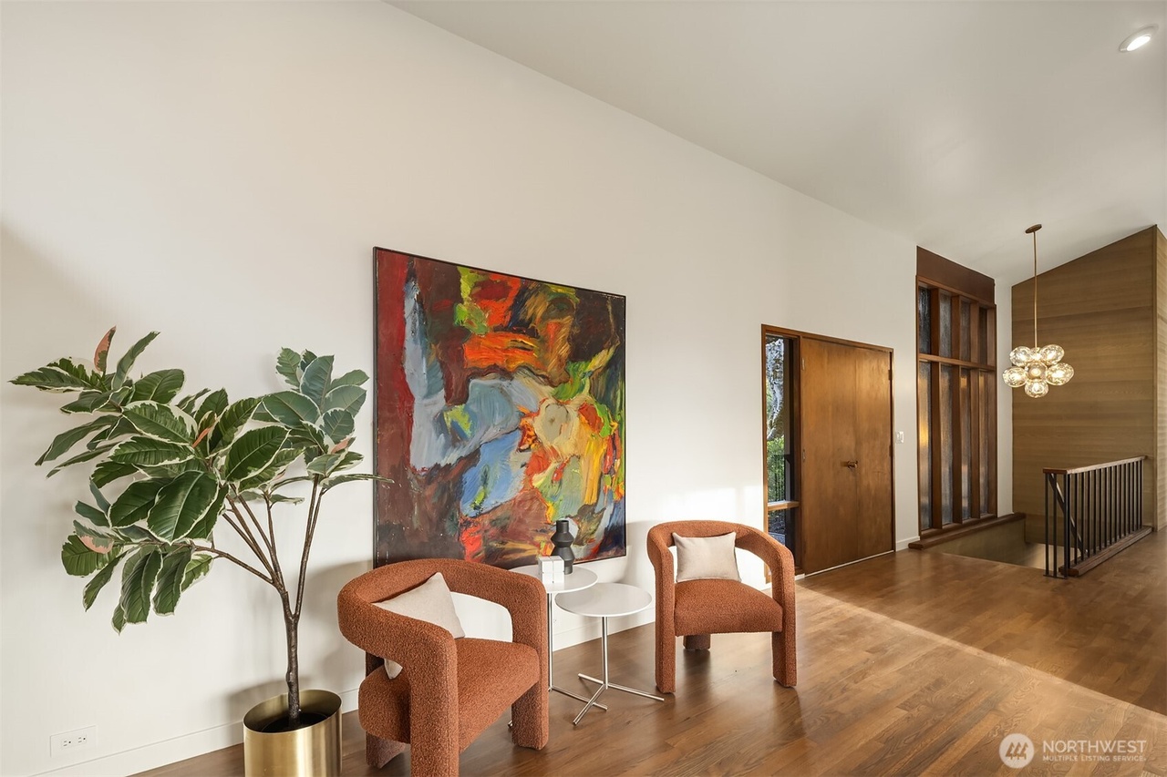 Modern entryway seating area with sculpted rust-colored armchairs and large abstract painting