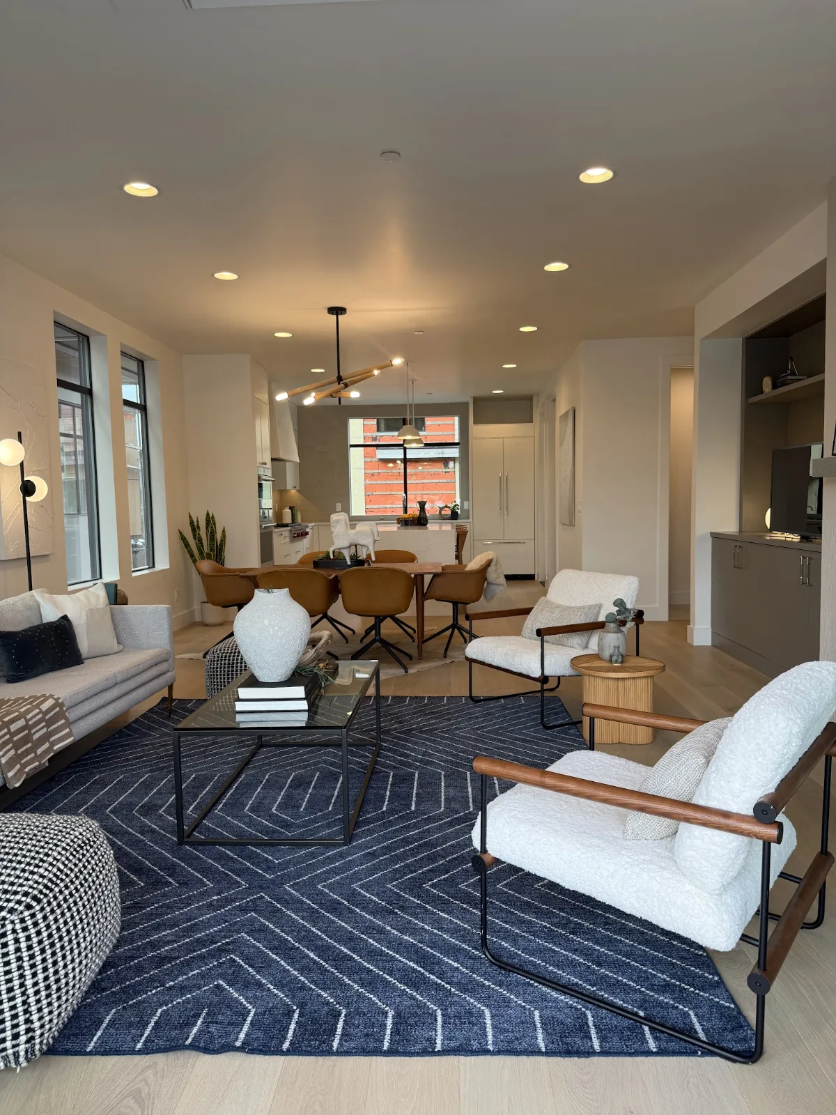Open-concept living and dining area in River Run model townhome featuring a navy geometric rug and white bouclé armchairs