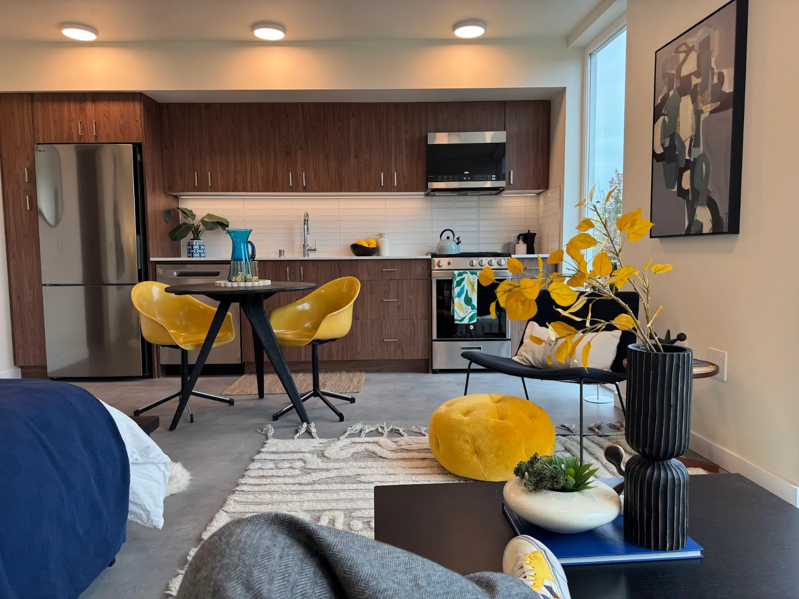 Walnut kitchen and compact dining nook with bright yellow chairs