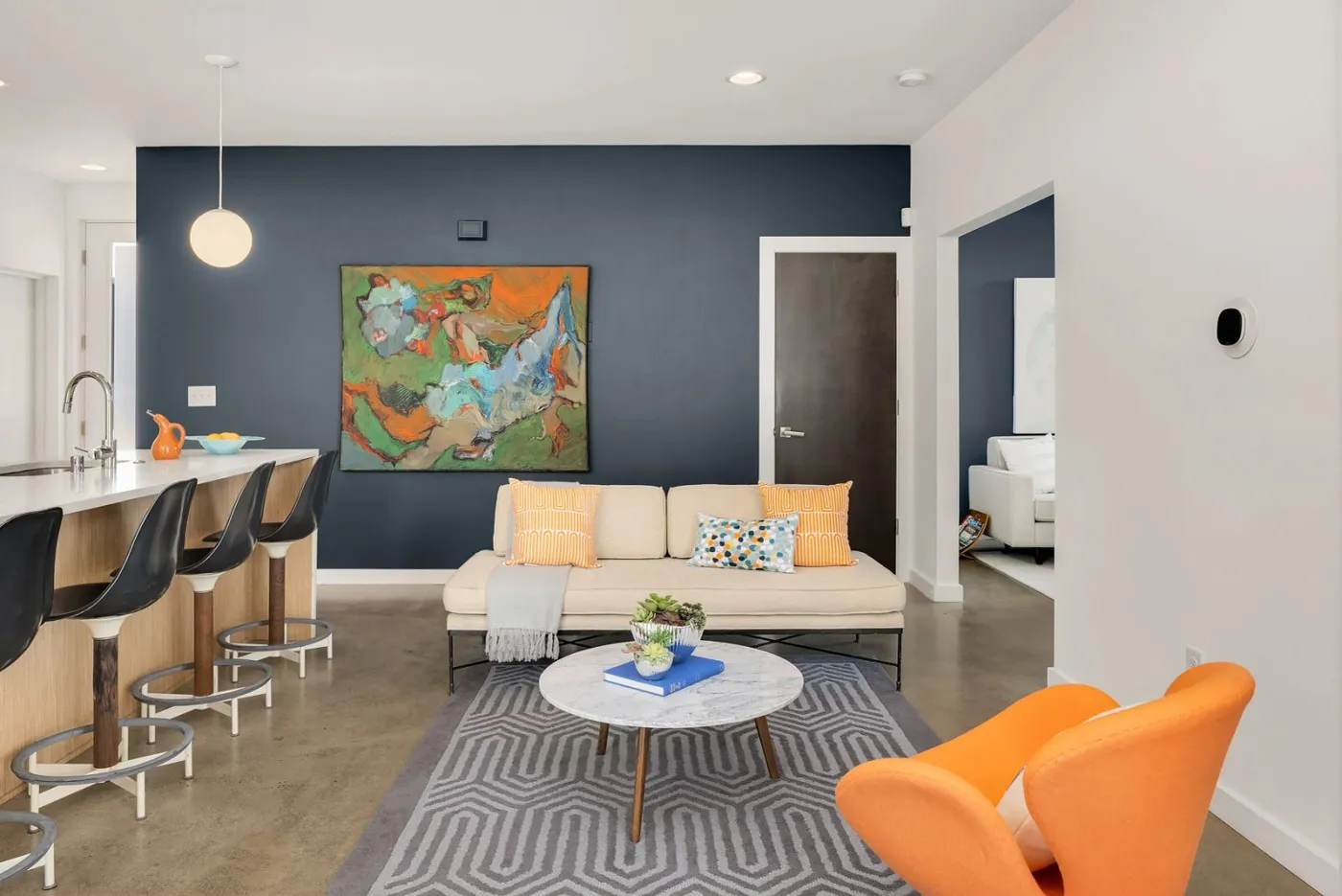 Living room with navy blue accent wall and orange armchair