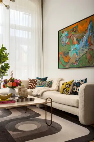 Capitol Hill Loft: A sunlit contemporary living room features a textured cream bouclé sofa decorated with eclectic throw pillows beneath a large abstract painting