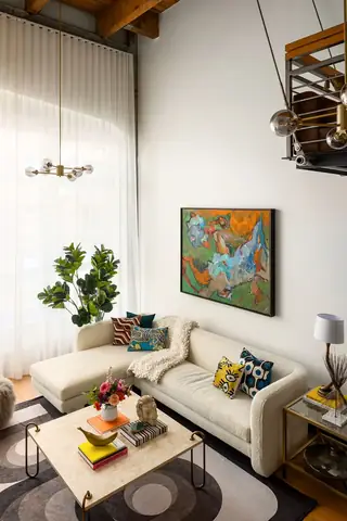 Capitol Hill Loft: A bright loft living room features a cream bouclé sectional sofa, marble coffee table, and vibrant abstract painting on high white walls