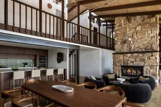 Edmonds Beach House: An expansive open-concept interior featuring a towering stone fireplace, wood-plank vaulted ceiling, lofted balcony, modern kitchen, and wooden dining area