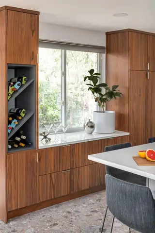 Greenwood Kitchen Design: Modern kitchen nook featuring rich walnut built-in cabinetry with a grey diagonal wine rack, white countertops, and a dining table with grey fabric chairs
