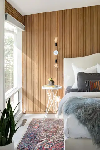 Issaquah Interior Design: A mid-century modern bedroom corner features vertical wood slat wall paneling, an upholstered bed, a slender white side table