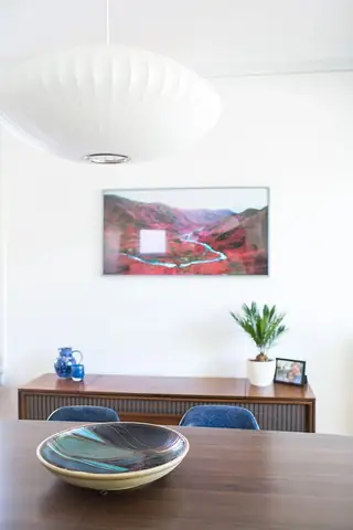 Madison Valley Design: A mid-century modern dining area features a large white saucer pendant lamp hanging above a dark wood table with a credenza