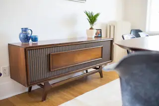 Madison Valley Design: A mid-century modern wooden credenza with slatted detailing sits against a white wall in a dining room