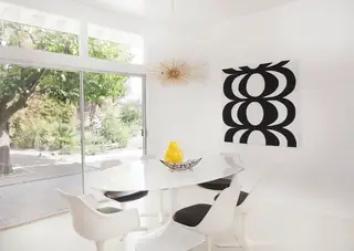 Pebble Beach Drive, Palm Springs: A sunlit mid-century modern dining room features a white oval tulip table paired with matching chairs, a gold starburst chandelier