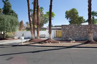 Pebble Beach Drive, Palm Springs: A mid-century modern home features a prominent stone facade wall, desert landscaping with palm trees