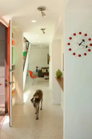 The Aqua Lair, Lake Sammamish: A bright mid-century modern entryway with terrazzo floors features an iconic red ball wall clock, orange door accents