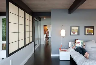 The Aqua Lair, Lake Sammamish: A mid-century modern bedroom features dark wood floors, a grey accent wall, Japanese-style shoji panels