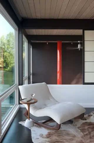 The Aqua Lair, Lake Sammamish: A white bouclé rocking chaise lounge and small pedestal side table rest on a cowhide rug in a modern living space