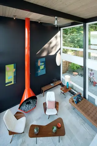 The Aqua Lair, Lake Sammamish: A high-ceilinged mid-century modern living room features a striking bright orange cone fireplace against a dark gray accent wall paired