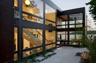 The Aqua Lair, Lake Sammamish: A modern two-story home features floor-to-ceiling glass windows, an illuminated interior with an open staircase
